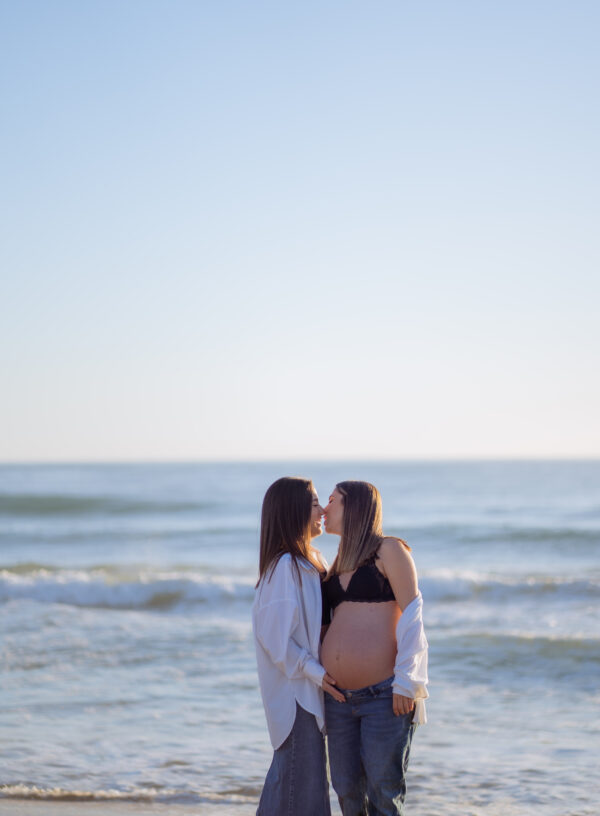 pareja de mujeres en la playa en una sesión de embarazo