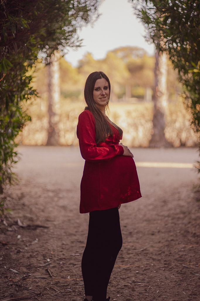 sesión de embarazo en exterior. Mujer embarazad vestida de rojo en el parque.
