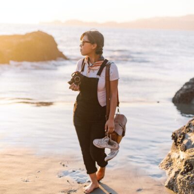 Chica con cámara de fotos en la playa. Paseo fotográfico.